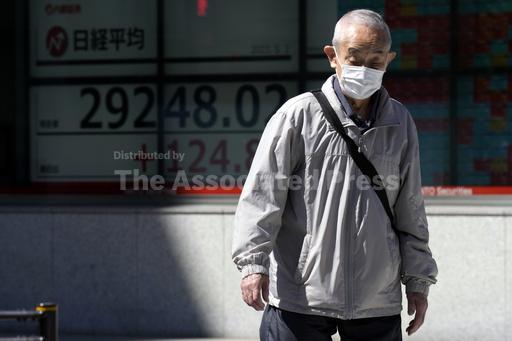 A person walks past an electronic stock board showing Japan